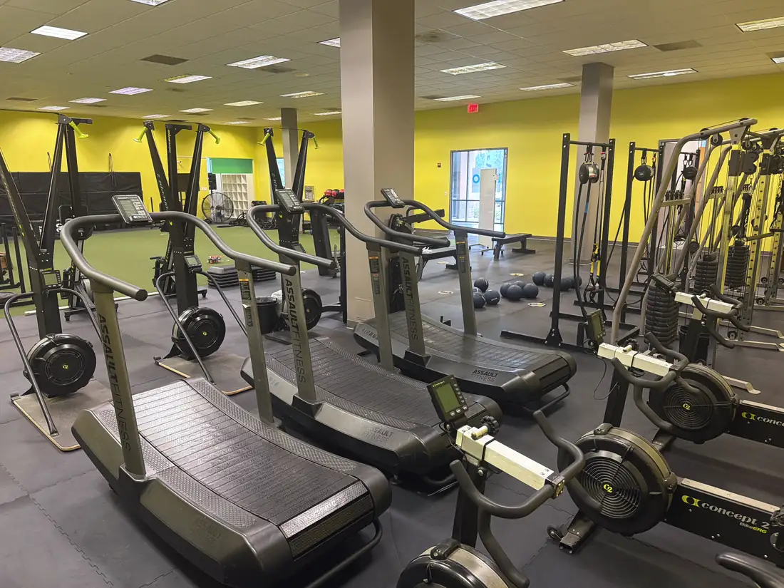 The turf hall at Chantilly: curved treadmills, SkiErgs and bike ergs in front of the turf and the yellow walls.
